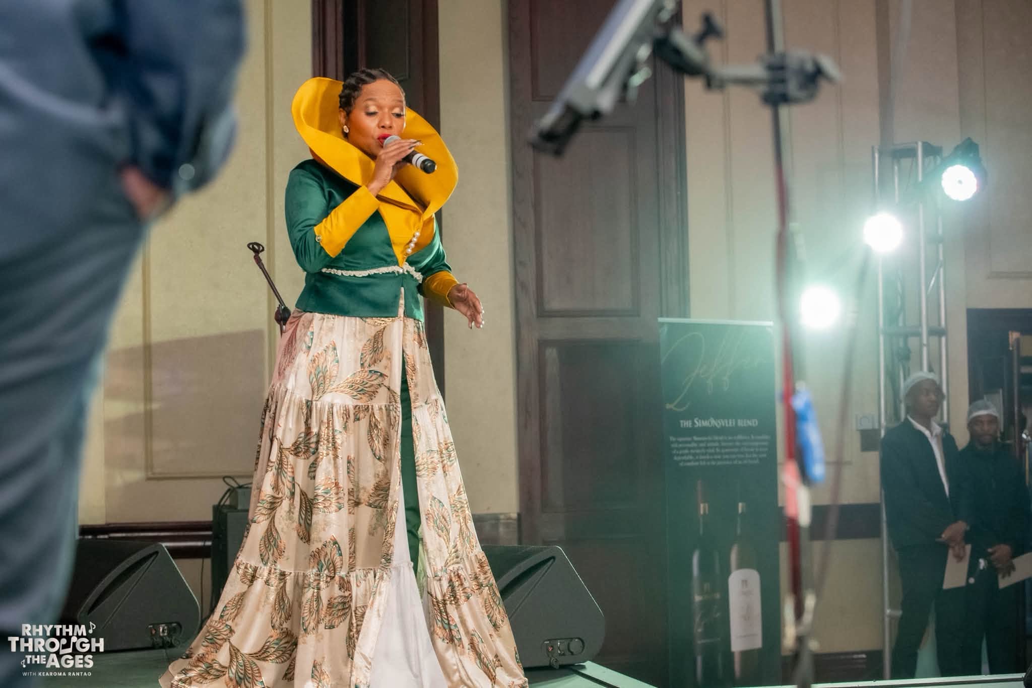 Kearoma Rantao on stage in an emerald and gold costume, singing